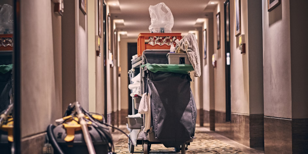 An empty corridor with a cleaning cart and vacuum cleaner in the middle.